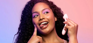Woman with purple eyeshadow and curly dark hair holding VUSH Shine G-Spot vibrator like a phone