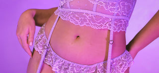 Close up of midrift in purple lingerie with suspenders against purple background